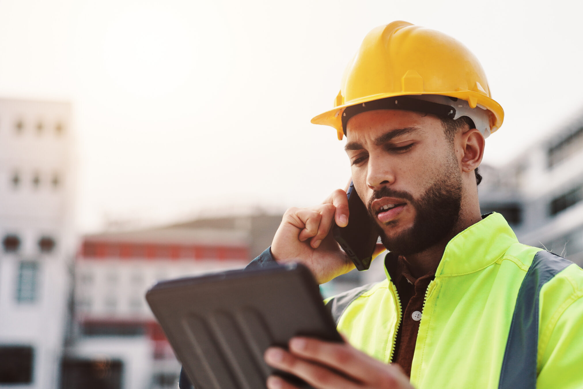 construction safety professional on the phone with coach wearing hard hat and safety vest PPE